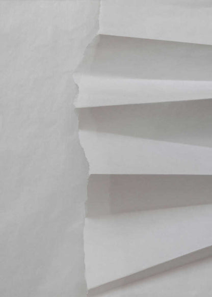 A minimalist composition of folded and torn white paper, showcasing geometric forms and shadows in a black frame.