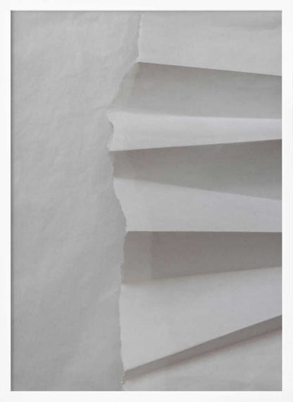 A minimalist composition of folded and torn white paper, showcasing geometric forms and shadows in a black frame.