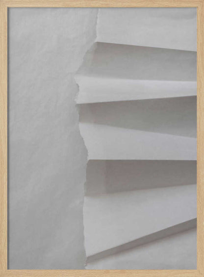 A minimalist composition of folded and torn white paper, showcasing geometric forms and shadows in a black frame.