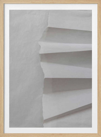 A minimalist composition of folded and torn white paper, showcasing geometric forms and shadows in a black frame.