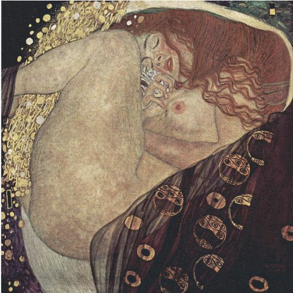 A print of Gustav Klimt's 1907 painting, 'Danaë'. The artwork depicts a sleeping, nude woman with vibrant red hair curled into a fetal position, receiving a shower of golden rain. The style is characteristic of Art Nouveau, with rich, decorative patterns on surrounding fabrics against a dark, star-like background, all within a light wood frame. Wall Art