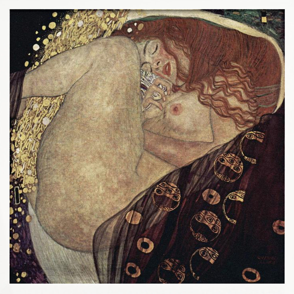 A print of Gustav Klimt's 1907 painting, 'Danaë'. The artwork depicts a sleeping, nude woman with vibrant red hair curled into a fetal position, receiving a shower of golden rain. The style is characteristic of Art Nouveau, with rich, decorative patterns on surrounding fabrics against a dark, star-like background, all within a light wood frame. Wall Art