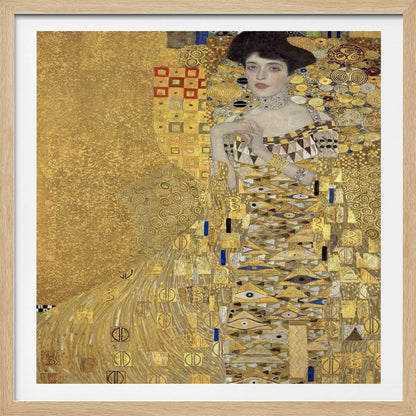 A framed print of Gustav Klimt's 'Portrait of Adele Bloch-Bauer I,' also known as 'The Woman in Gold.' The painting depicts a woman in an ornate, gilded gown covered in intricate patterns, blending into a shimmering gold background characteristic of the Art Nouveau style. Poster