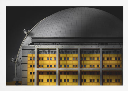 A framed architectural photograph with selective color, featuring a bright yellow building in the foreground against a monochrome background of a large grey dome structure under a black sky. Wall Art