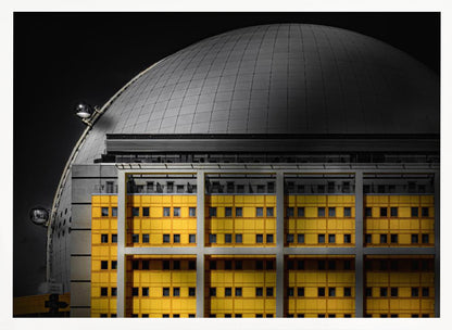 A framed architectural photograph with selective color, featuring a bright yellow building in the foreground against a monochrome background of a large grey dome structure under a black sky. Wall Art