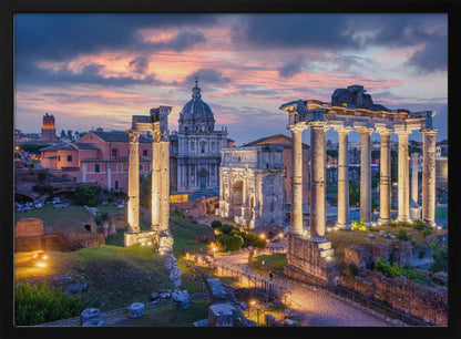 A scenic photograph of the ancient Roman Forum in Rome, Italy, at dusk. The ruins, including prominent columns and arches, are illuminated by warm lights, contrasting with the deep blue and vibrant pink of the sunset sky. Wall Art