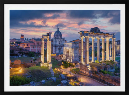 A scenic photograph of the ancient Roman Forum in Rome, Italy, at dusk. The ruins, including prominent columns and arches, are illuminated by warm lights, contrasting with the deep blue and vibrant pink of the sunset sky. Wall Art