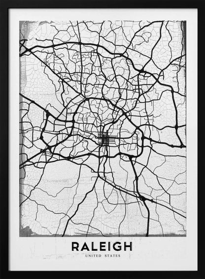 A minimalist black and white street map of Raleigh, North Carolina, displayed in a black frame. The map features black lines representing roads on a distressed, crackled white background. At the bottom, the word 'RALEIGH' is printed in a bold, black, sans-serif font. Print