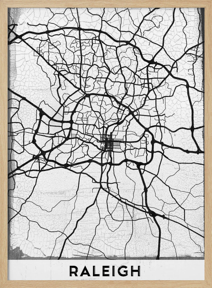 A minimalist black and white street map of Raleigh, North Carolina, displayed in a black frame. The map features black lines representing roads on a distressed, crackled white background. At the bottom, the word 'RALEIGH' is printed in a bold, black, sans-serif font. Print