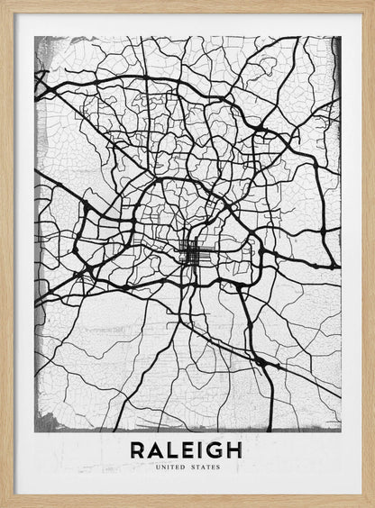 A minimalist black and white street map of Raleigh, North Carolina, displayed in a black frame. The map features black lines representing roads on a distressed, crackled white background. At the bottom, the word 'RALEIGH' is printed in a bold, black, sans-serif font. Print