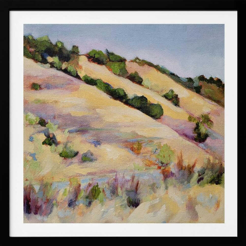 An impressionist oil painting of golden, rolling hills dotted with green shrubs under a pale blue sky, framed in light wood.
