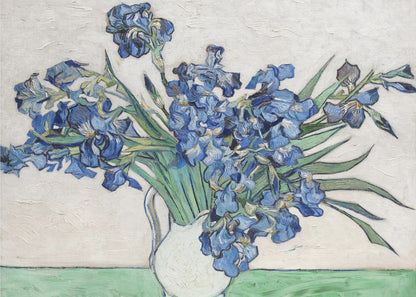 A framed print of Vincent van Gogh's famous painting 'Irises'. It features a large bouquet of vibrant blue iris flowers with long green leaves, arranged in a simple white pitcher. The background is a textured off-white wall, and the pitcher rests on a light green surface. The painting is in the post-impressionist style with thick, visible brushstrokes. Wall Art