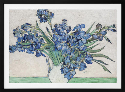A framed print of Vincent van Gogh's famous painting 'Irises'. It features a large bouquet of vibrant blue iris flowers with long green leaves, arranged in a simple white pitcher. The background is a textured off-white wall, and the pitcher rests on a light green surface. The painting is in the post-impressionist style with thick, visible brushstrokes. Wall Art