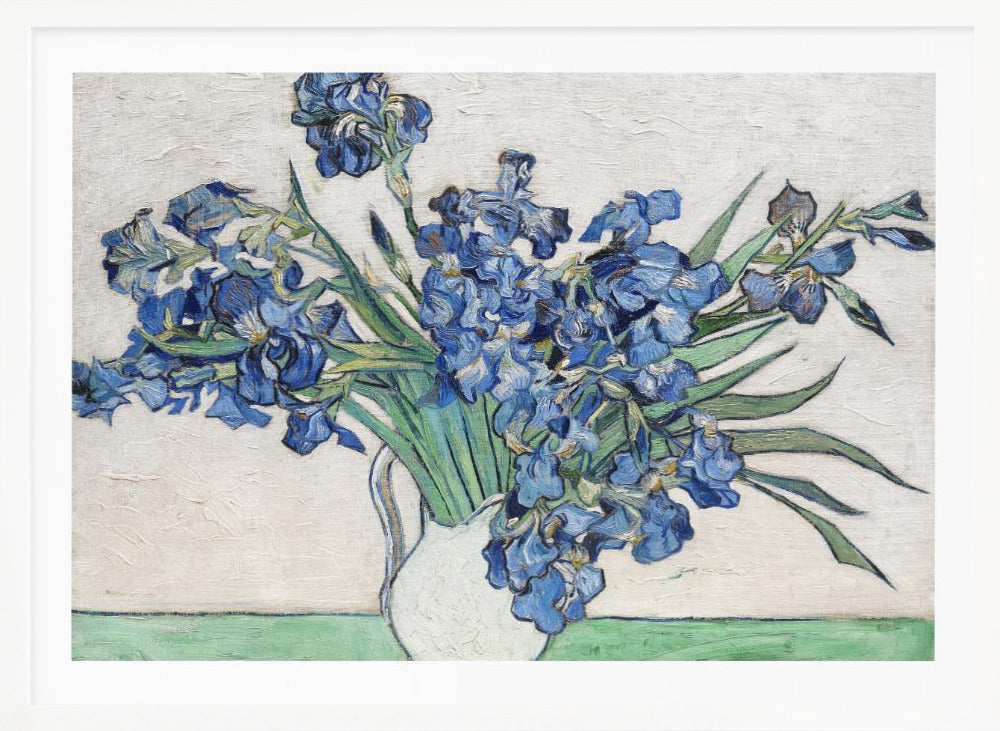 A framed print of Vincent van Gogh's famous painting 'Irises'. It features a large bouquet of vibrant blue iris flowers with long green leaves, arranged in a simple white pitcher. The background is a textured off-white wall, and the pitcher rests on a light green surface. The painting is in the post-impressionist style with thick, visible brushstrokes. Wall Art