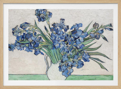 A framed print of Vincent van Gogh's famous painting 'Irises'. It features a large bouquet of vibrant blue iris flowers with long green leaves, arranged in a simple white pitcher. The background is a textured off-white wall, and the pitcher rests on a light green surface. The painting is in the post-impressionist style with thick, visible brushstrokes. Wall Art