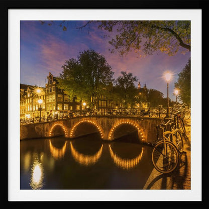 An idyllic nightscape view of Keizersgracht canal in Amsterdam, featuring illuminated buildings reflecting on the water under a dark sky. Wall Art
