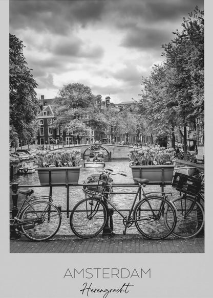 A black and white poster of the Herengracht canal in Amsterdam. In the foreground, two bicycles are parked by a railing with flower boxes. In the background, there's a classic view of the canal with a bridge, canal houses, and boats under a cloudy sky. The bottom of the poster has text that reads 'AMSTERDAM Herengracht NEDERLAND'. Decor