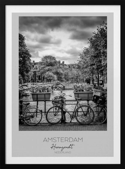 A black and white poster of the Herengracht canal in Amsterdam. In the foreground, two bicycles are parked by a railing with flower boxes. In the background, there's a classic view of the canal with a bridge, canal houses, and boats under a cloudy sky. The bottom of the poster has text that reads 'AMSTERDAM Herengracht NEDERLAND'. Decor