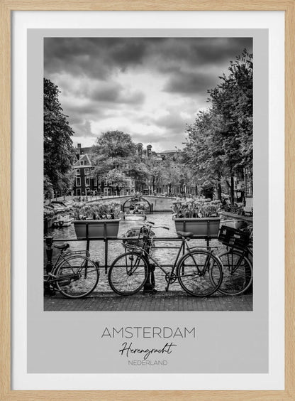 A black and white poster of the Herengracht canal in Amsterdam. In the foreground, two bicycles are parked by a railing with flower boxes. In the background, there's a classic view of the canal with a bridge, canal houses, and boats under a cloudy sky. The bottom of the poster has text that reads 'AMSTERDAM Herengracht NEDERLAND'. Decor