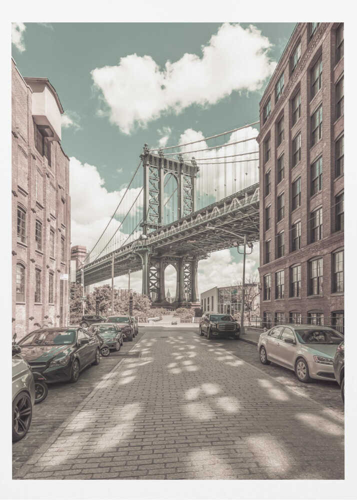 A vertical photograph of the Manhattan Bridge from a cobblestone street in DUMBO, Brooklyn, framed by tall brick buildings. The image has a vintage aesthetic with a muted teal sky and sepia-toned buildings and streets. Print
