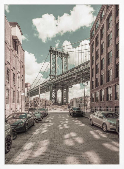 A vertical photograph of the Manhattan Bridge from a cobblestone street in DUMBO, Brooklyn, framed by tall brick buildings. The image has a vintage aesthetic with a muted teal sky and sepia-toned buildings and streets. Print