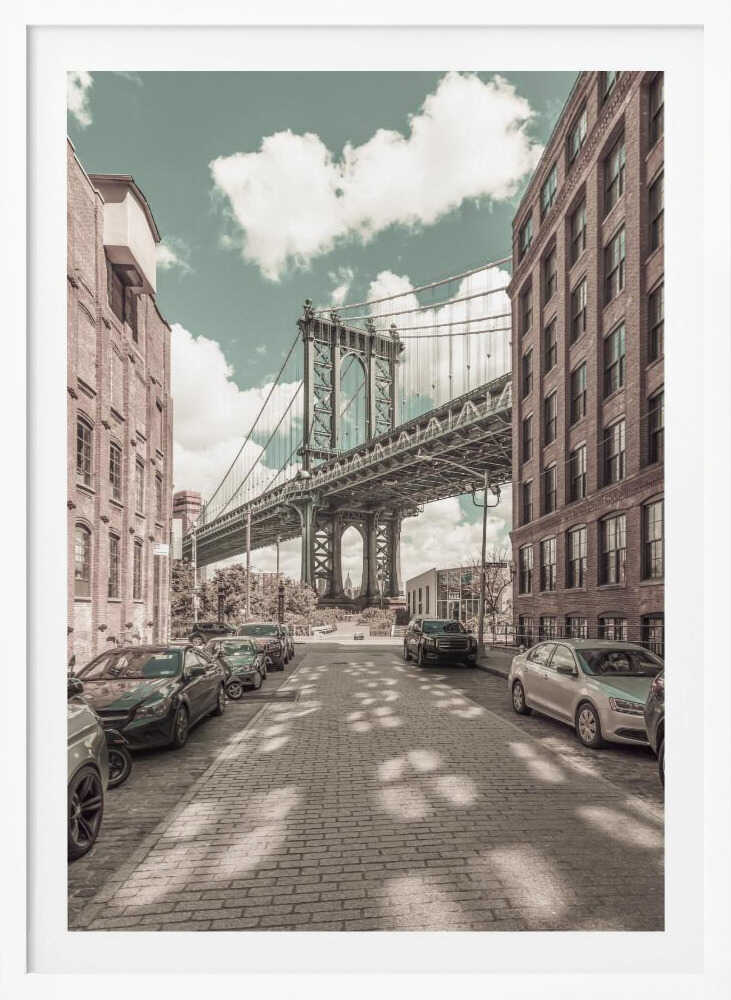 A vertical photograph of the Manhattan Bridge from a cobblestone street in DUMBO, Brooklyn, framed by tall brick buildings. The image has a vintage aesthetic with a muted teal sky and sepia-toned buildings and streets. Print