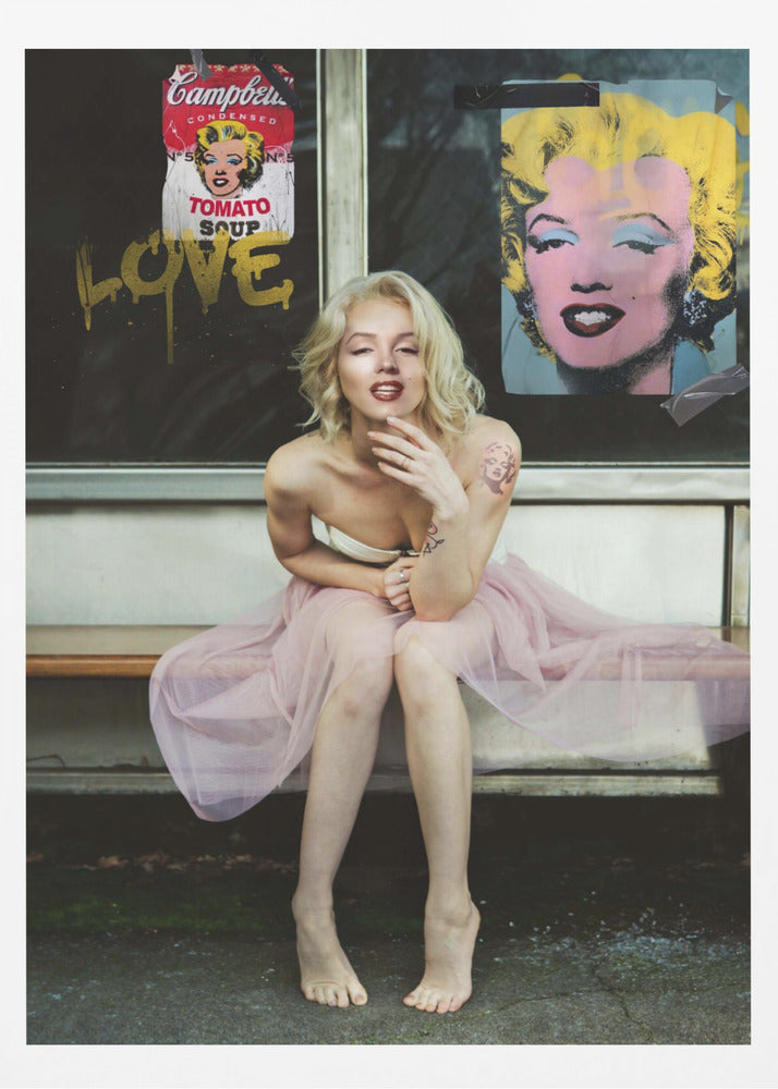 A blonde woman styled like Marilyn Monroe sits on a bench, wearing a pink tulle skirt. Behind her, a dark window features an Andy Warhol-style poster of Monroe, a Campbell's soup can parody, and the word 'LOVE' in gold graffiti. Artwork