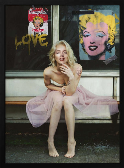A blonde woman styled like Marilyn Monroe sits on a bench, wearing a pink tulle skirt. Behind her, a dark window features an Andy Warhol-style poster of Monroe, a Campbell's soup can parody, and the word 'LOVE' in gold graffiti. Artwork