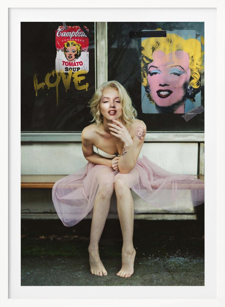 A blonde woman styled like Marilyn Monroe sits on a bench, wearing a pink tulle skirt. Behind her, a dark window features an Andy Warhol-style poster of Monroe, a Campbell's soup can parody, and the word 'LOVE' in gold graffiti. Artwork