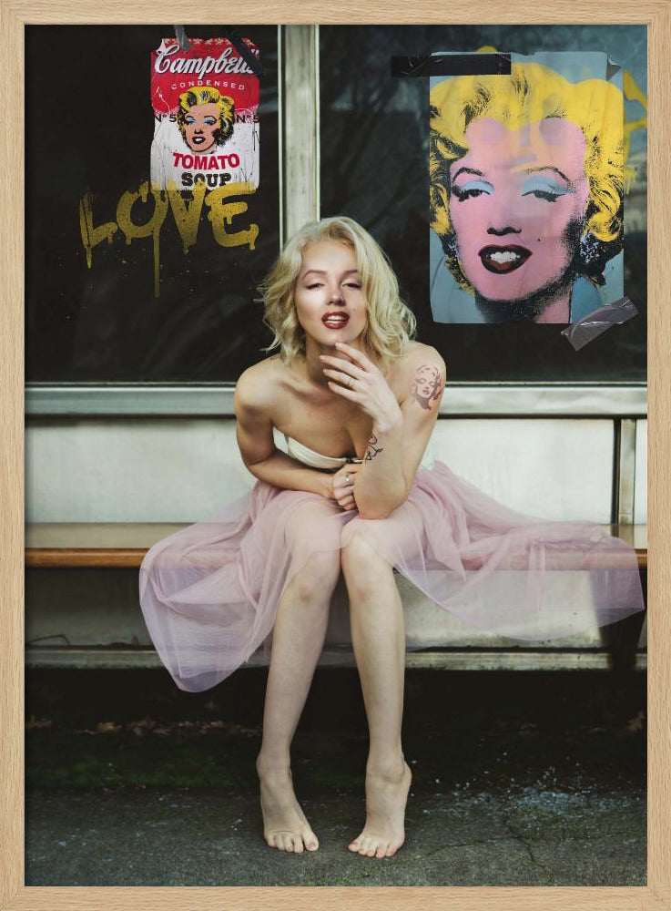 A blonde woman styled like Marilyn Monroe sits on a bench, wearing a pink tulle skirt. Behind her, a dark window features an Andy Warhol-style poster of Monroe, a Campbell's soup can parody, and the word 'LOVE' in gold graffiti. Artwork