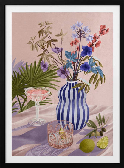 A vibrant still life painting featuring a blue and white striped wavy vase filled with a colorful bouquet of flowers. To the left is a pink cocktail in a coupe glass and a decorative tumbler. In the foreground, there are fresh limes and an olive branch. The scene is set on a draped pink cloth against a soft pink background with shadows from palm leaves. Artwork