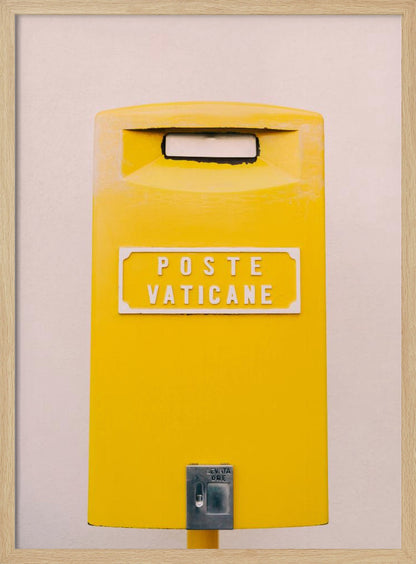 A close-up, front-view photograph of a vibrant yellow Vatican City mailbox against a plain beige wall, enclosed in a thin black frame. The words 'POSTE VATICANE' are printed in white on the front. Artwork