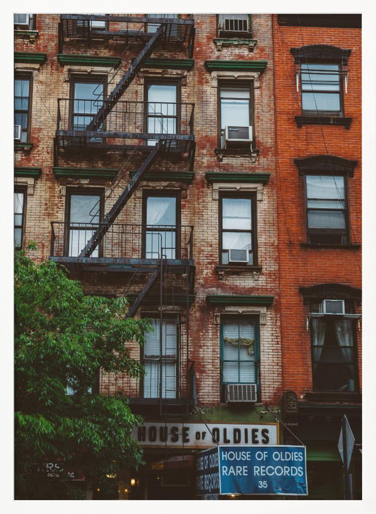 A classic multi-story brick apartment building with a prominent black metal fire escape zigzagging across its facade. A sign for a 'House of Oldies' rare records shop is visible on the ground floor. Poster