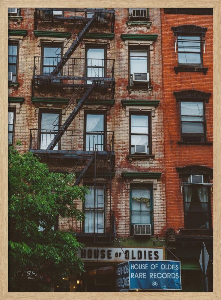 A classic multi-story brick apartment building with a prominent black metal fire escape zigzagging across its facade. A sign for a 'House of Oldies' rare records shop is visible on the ground floor. Poster