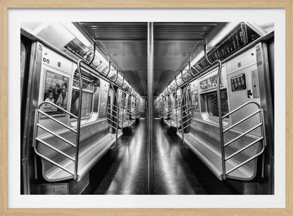 A framed, black and white photograph capturing a perfectly symmetrical view down the aisle of an empty subway car. The reflective, dark floor and the metallic seats and handrails create strong leading lines, giving the image a sense of depth and urban solitude. Wall Art