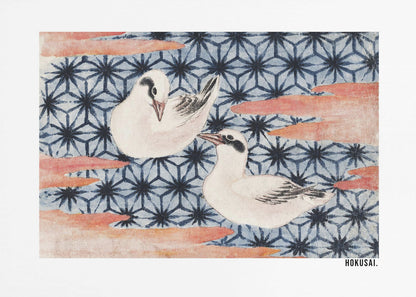 A classic Japanese woodblock print by Hokusai featuring two white birds with black eye markings resting on a background of a traditional blue Asanoha geometric pattern. Soft, reddish-orange cloud-like shapes float across the scene. Print