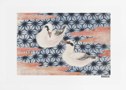A classic Japanese woodblock print by Hokusai featuring two white birds with black eye markings resting on a background of a traditional blue Asanoha geometric pattern. Soft, reddish-orange cloud-like shapes float across the scene. Print