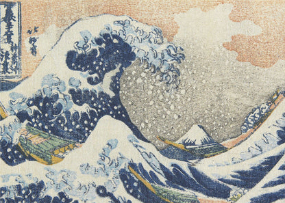 A framed reproduction of Hokusai's 'The Great Wave off Kanagawa,' depicting a massive, curling blue wave with white foam cresting over fishing boats. In the background, a small, snow-capped Mount Fuji stands under a pale orange and grey sky. Poster