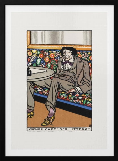 A framed art print titled 'Wiener Cafe: Der Litterat', depicting a stylized illustration of a writer in a Viennese cafe. The man, with a gaunt face and dark hair, sits on a brightly colored, floral-patterned bench, wearing a grey suit, striped socks, and yellow shoes. A table beside him holds an inkwell and quill. Decor