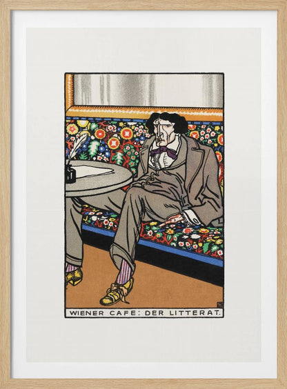 A framed art print titled 'Wiener Cafe: Der Litterat', depicting a stylized illustration of a writer in a Viennese cafe. The man, with a gaunt face and dark hair, sits on a brightly colored, floral-patterned bench, wearing a grey suit, striped socks, and yellow shoes. A table beside him holds an inkwell and quill. Decor