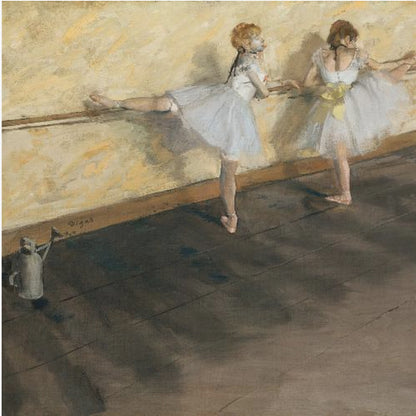 A framed impressionist painting by Edgar Degas depicting two ballet dancers in white tutus practicing at a barre. The studio has a yellow wall and a dark brown wooden floor. One dancer stretches her leg on the barre while the other stands beside her. Artwork