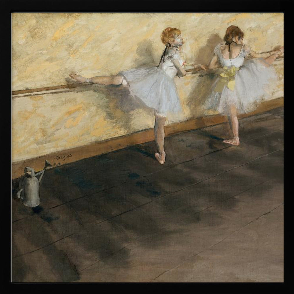A framed impressionist painting by Edgar Degas depicting two ballet dancers in white tutus practicing at a barre. The studio has a yellow wall and a dark brown wooden floor. One dancer stretches her leg on the barre while the other stands beside her. Artwork