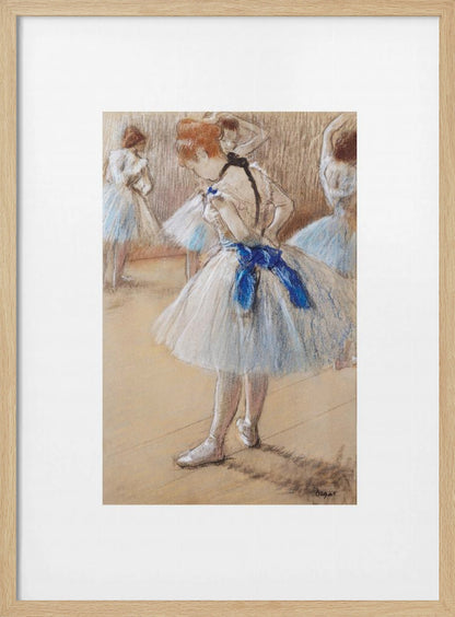 A framed print of an impressionist pastel drawing by Edgar Degas. It shows a ballerina in a white and light blue tutu with a prominent royal blue sash. She is viewed from the side as she adjusts her costume, with other dancers blurred in the background of a dance studio. Poster