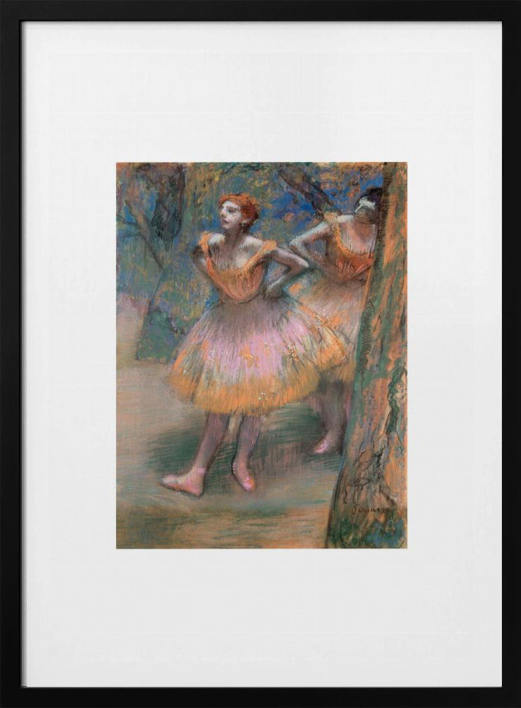 A framed vertical print of Edgar Degas's impressionist pastel drawing 'Dancers, Pink and Green'. It depicts two ballerinas in pink and orange tutus standing backstage amongst trees, captured in soft, expressive strokes. Artwork
