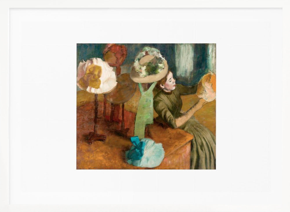 A framed print of Edgar Degas's Impressionist painting 'The Millinery Shop,' showing a woman in a green dress examining a hat in a shop filled with various fashionable hats on display stands. Print