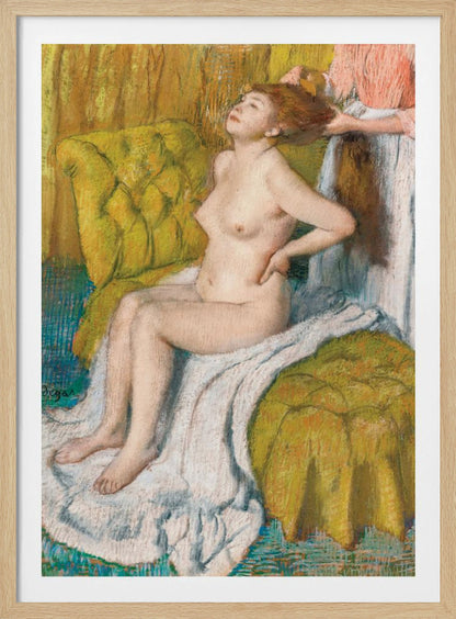 A pastel drawing by Edgar Degas of a nude woman with red hair sitting on a plush, chartreuse armchair. She leans her head back in pleasure as another person, likely a maid, stands behind her and combs her hair. The scene is intimate and rendered in an impressionistic style with visible pastel strokes. Artwork