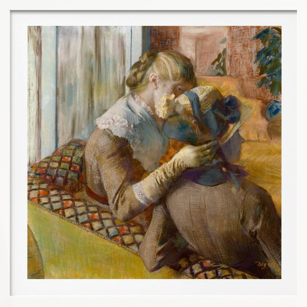 A framed Impressionist painting by Edgar Degas depicting two women. One woman, with blonde hair tied back, adjusts a hat with a blue ribbon on the other woman who is sitting with her back mostly to the viewer on a colorful patterned sofa. Print
