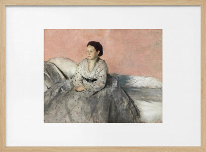 A framed impressionist painting of a woman with dark hair sitting on a bed against a dusty rose background. She wears a white, dotted blouse and a voluminous gray skirt, looking thoughtfully to her left. The painting is set in a silver frame with a white mat. Poster