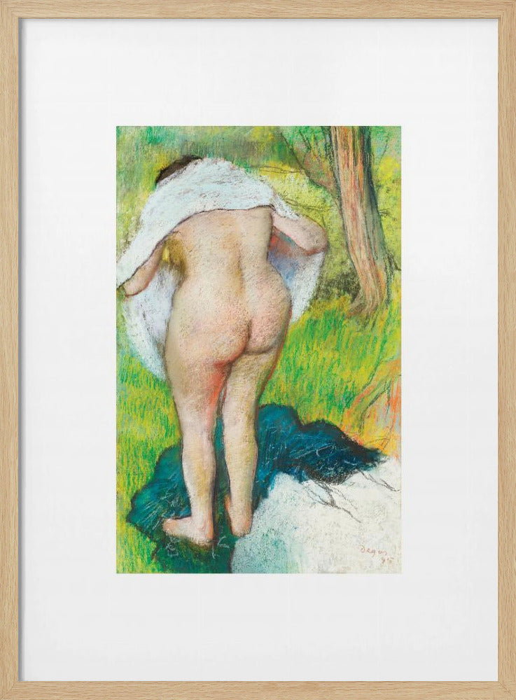 A framed pastel artwork by Edgar Degas showing the back of a nude woman as she dries herself with a white towel in a lush green landscape. The impressionist style is evident in the soft, textured application of color. Artwork