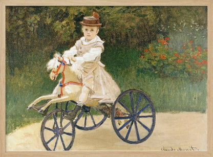An Impressionist painting by Claude Monet depicting his son, Jean, riding a toy horse tricycle. The young boy wears a brown hat and a light-colored outfit, sitting on a white hobby horse with large blue wheels, set against a lush green garden background. Decor